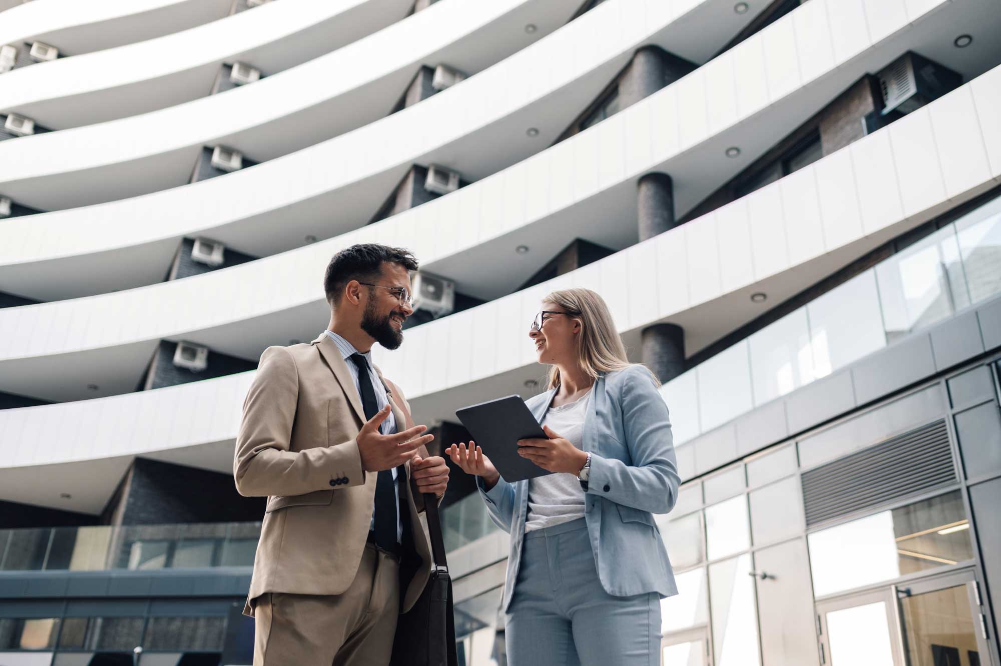 Business people having conversation about work outdoors while using digital tablet