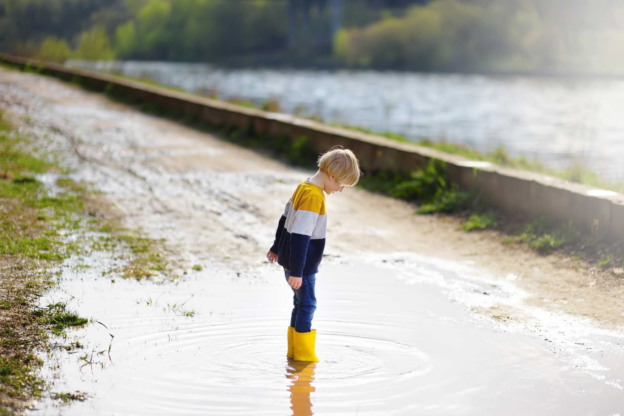 child wearing rain boots in a puddle