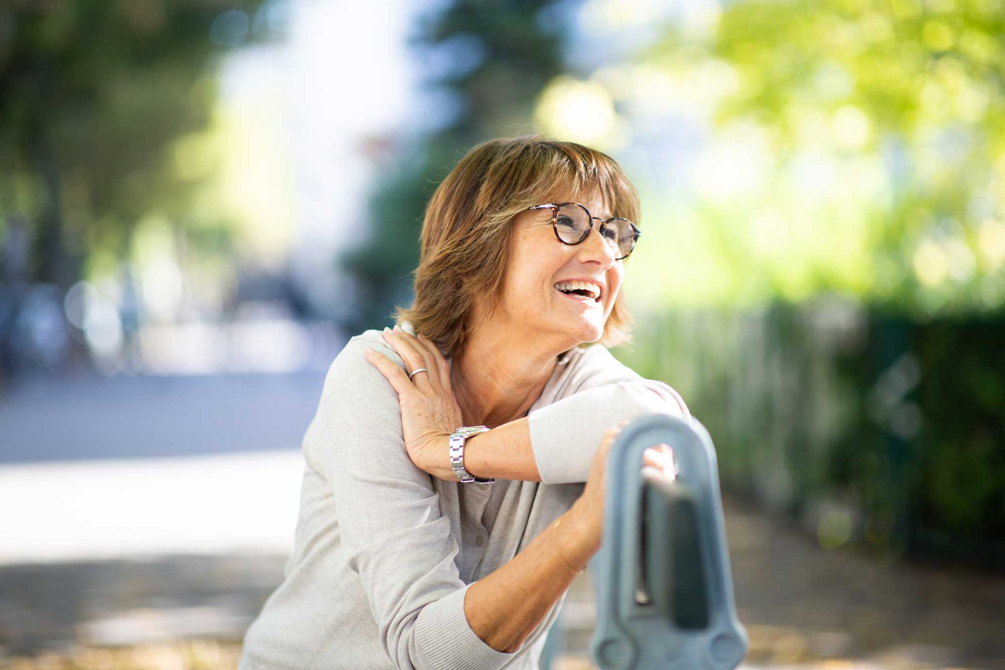 Close up older woman sitting on park bench laughing