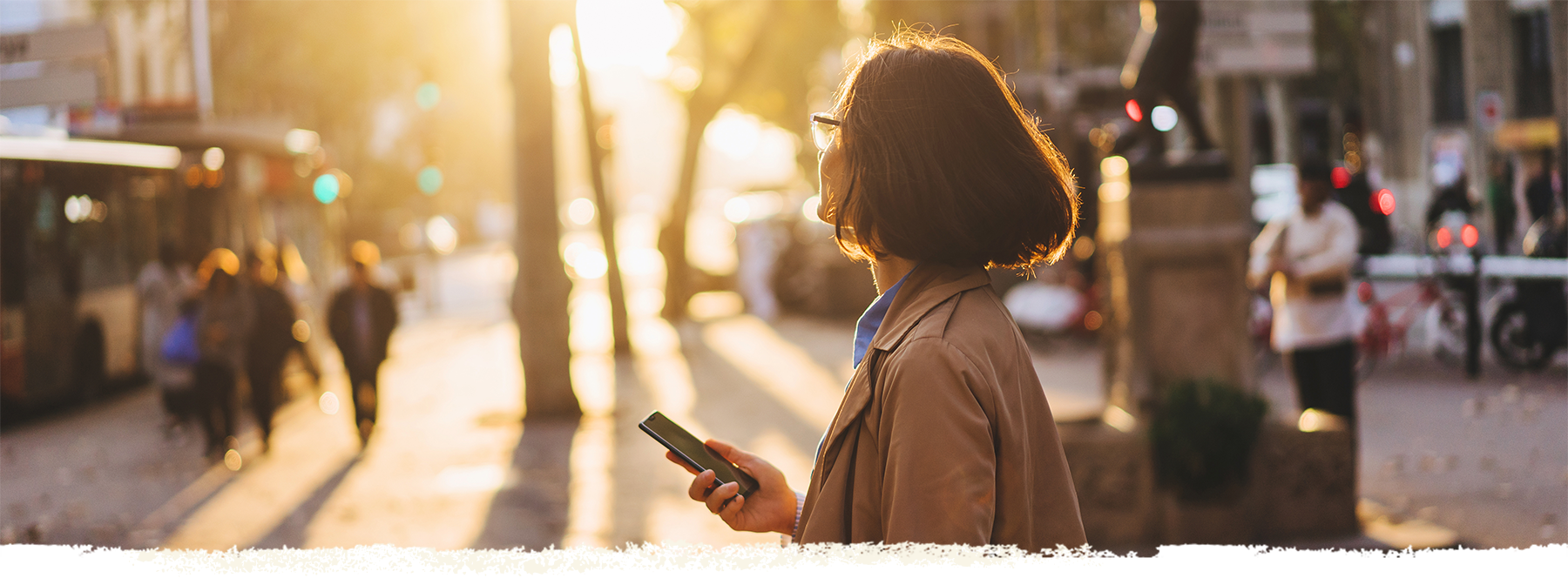 Girl enjoying sunset and chatting with friends via smartphone on the city streets